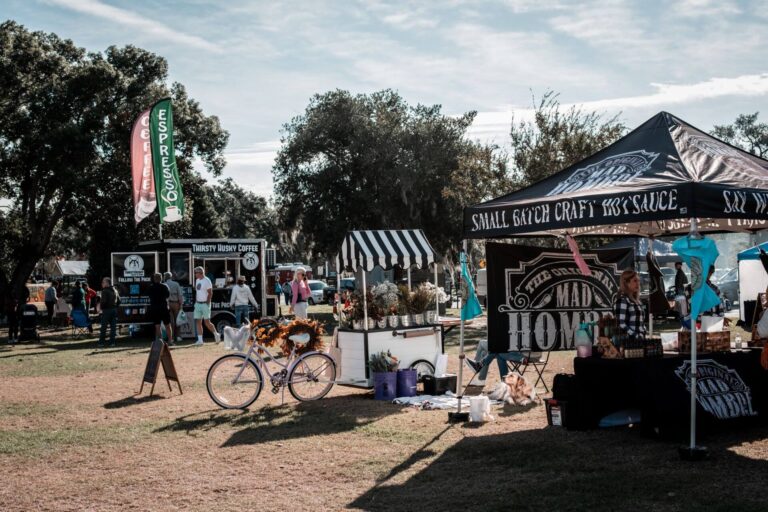 Outdoor food stalls and a food truck at a sunny park market