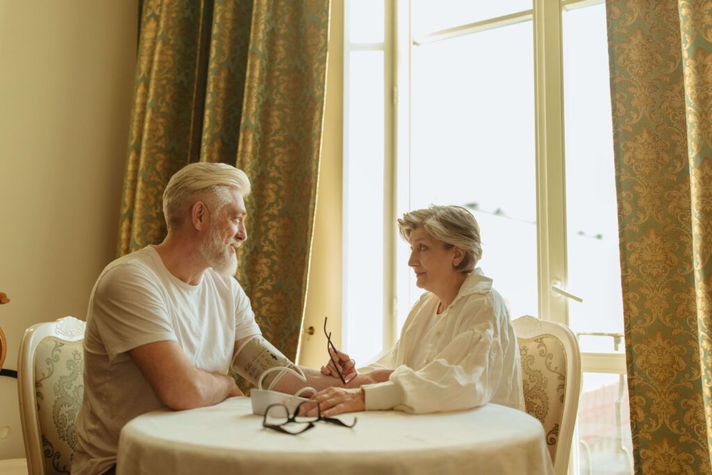 Senior couple using a digital blood pressure monitor during a health check.