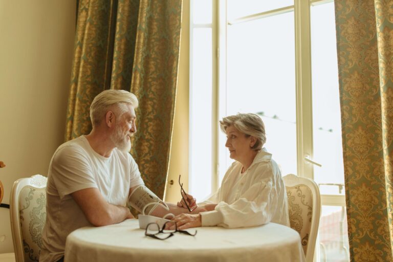 Senior couple using a digital blood pressure monitor during a health check.